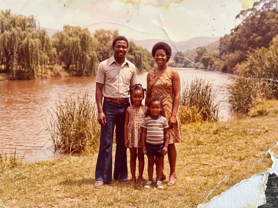 A cracked, stained 1970s photo of a family by a river